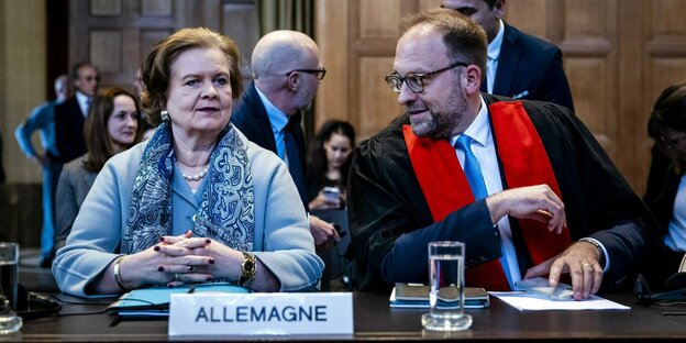 Eine Frau sitzt im Gericht, vor sich das Schild Allemagne