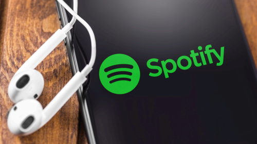 Apple Earpods and iPhone with Spotify logo on the screen. Spotify - online streaming audio service.