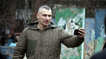 Kiews Bürgermeister Vitali Klitschko filmt sich mit einem Smartphone vor einem Wohngebäude. (Archiv)