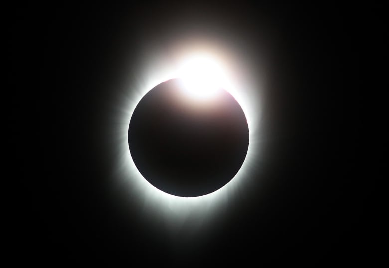 A white ring against a black background with a burst of light near the top.