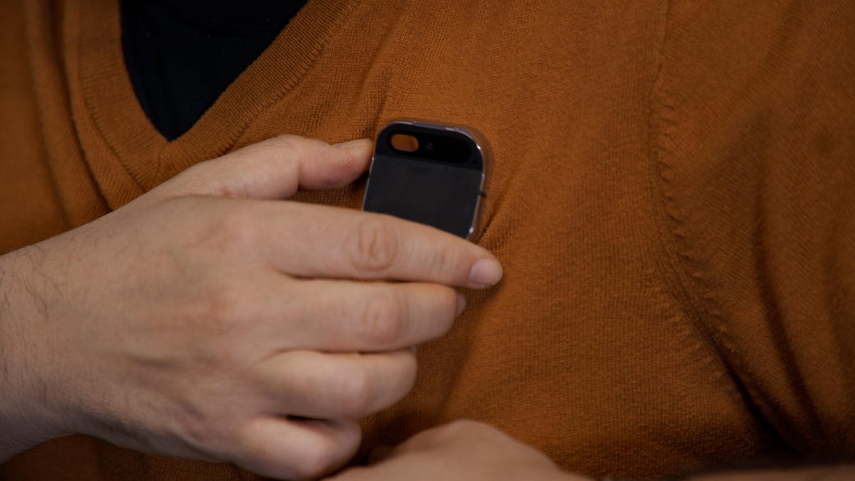 Holding the AI Pin from Humane attached to a sweater