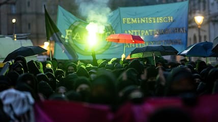 Teilnehmerinnen der linken Demonstration "Take back the night" in Berlin-Kreuzberg verwenden 2023 Regenschirme als Sichtschutz.