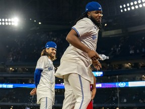 Blue Jays first baseman Vladimir Guerrero Jr., right, sprays water on Bo Bichette after defeating the Mariners at the Rogers Centre in Toronto, April 9, 2024.