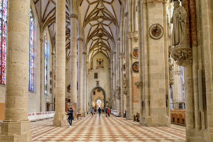 Blick in das Innere einer gotischen Kirche mit ein paar Besuchern.