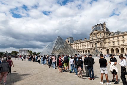 Hunderte Menschen stehen in einer langen Schlange vor dem Louvre in Paris.