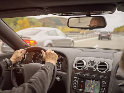 Älterer Mann im Auto auf Straße in der Schweiz.