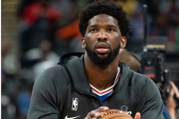 Joel Embiid holds a basketball and prepares for a shot.