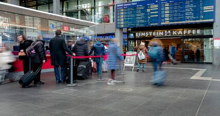 Reisende stehen vor der Information und der Anzeigetafel am Berliner Hauptbahnhof.