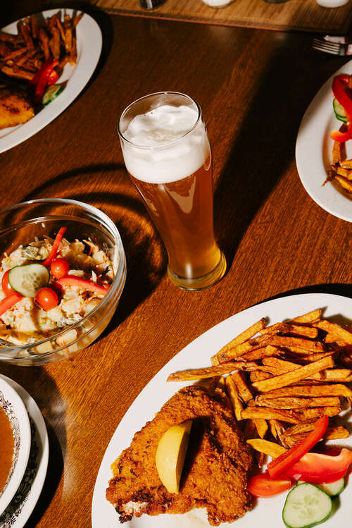 Ein Glas Bier und Teller mit Pommes Frites und anderen Speisen in einem Gasthof