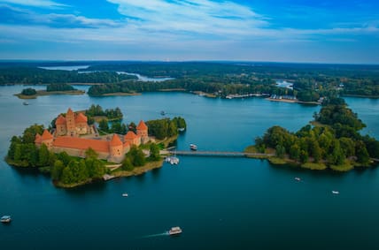 Luftaugnahme der Wasserburg von Trakai mit ihren roten Türmen, umgeben von einem blauen See und grünen Wäldern