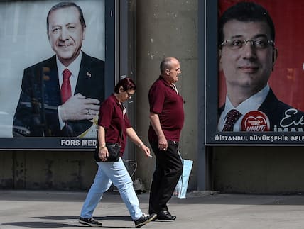 Ein Mann und eine Frau gehen an Plakaten des Präsidenten der Türkei, Erdogan (links), und des Bürgermeisters von Istanbul, Imamoglu, vorbei (Archivbild).