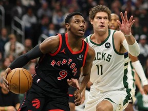 Raptors' RJ Barrett (left) drives around the Bucks' Brook Lopez (right) during first half NBA action at Fiserv Forum in Milwaukee, Friday, April 5, 2024.