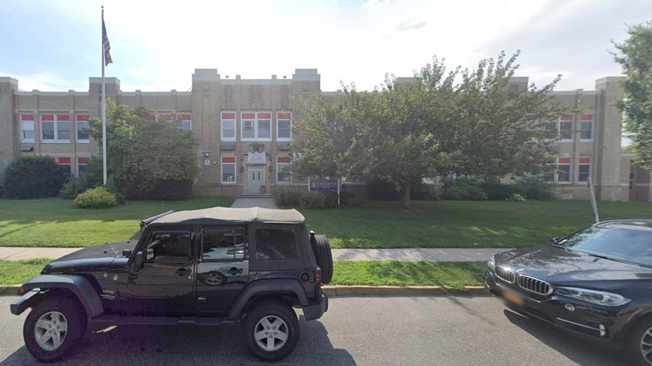 Schechter School of Long Island exterior shows a large brick building with an American flag out front and a Jeep parked in the foreground