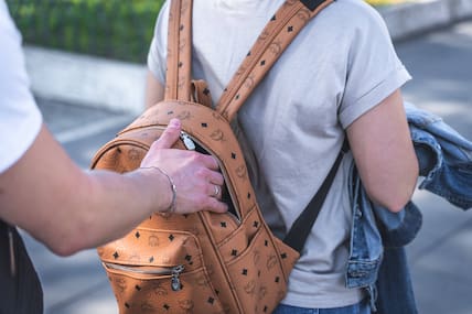 Ein Mann greift von hinten in einen Rucksack.