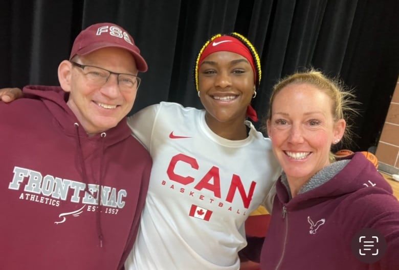 A young woman with her arms around an older man and woman, all three smiling.