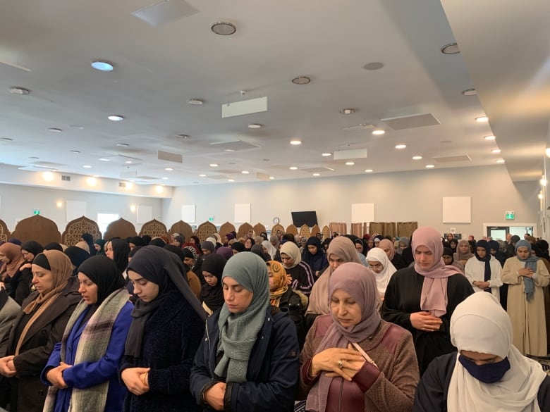 Women wearing headscarves pray at a mosque 