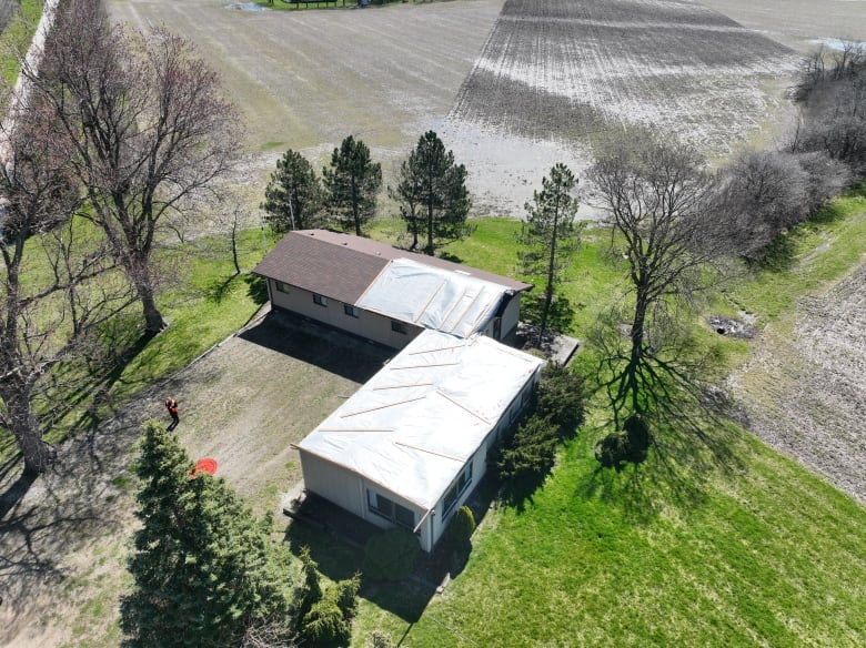 A mobile home pictures from above with tarps on the roof