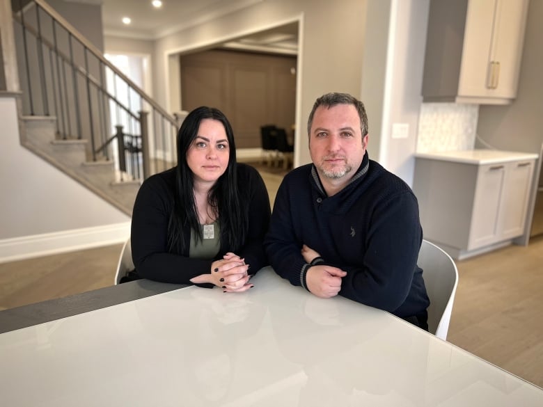 A man and woman sit at a kitchen table.