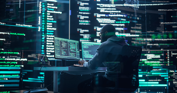 Black Male Developer Thinking and Typing on Computer, Surrounded by Big Screens Showing Coding Prompts. Professional Programmer Creating Software, Running Coding Tests. Futuristic Programming Concept