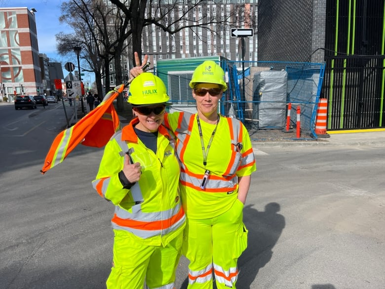 two women in bright yellow uniforms and hard hats