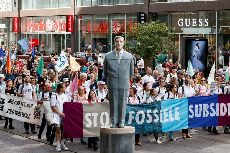 Protesters carrying signs and banners march down a street.