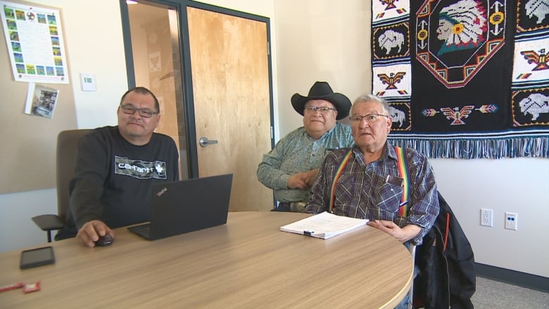 Three men sit around a table to talk with CBC on their concerns.