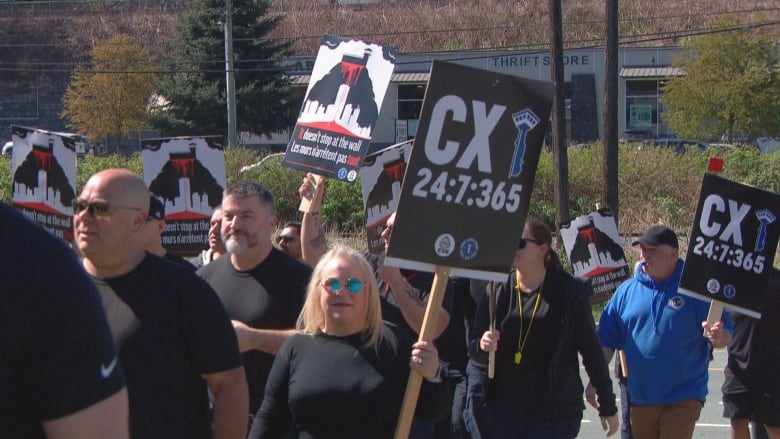 People holding signs march in a parking lot.