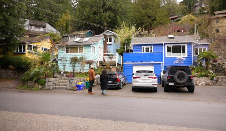 A man and woman stand in front of a row of colourful cottages.