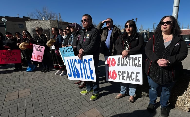 A group of people holding signs reading "Justice" and "No Justice No Peace."