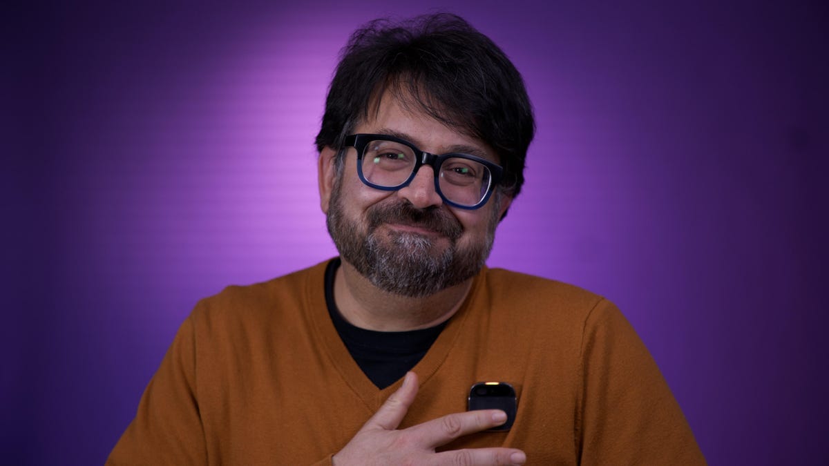 CNET Editor Scott Stein tapping on a Humane AI Pin on his orange sweater