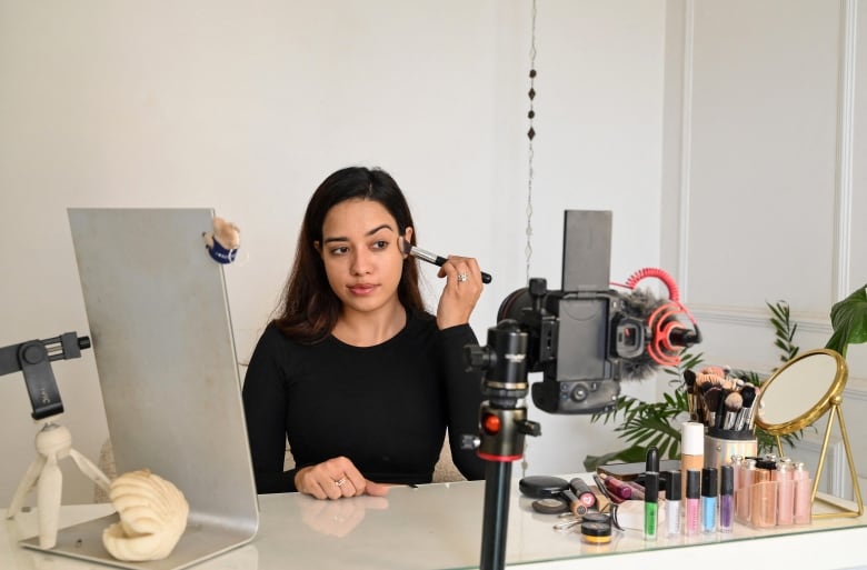 A woman does her makeup in front of a ring light