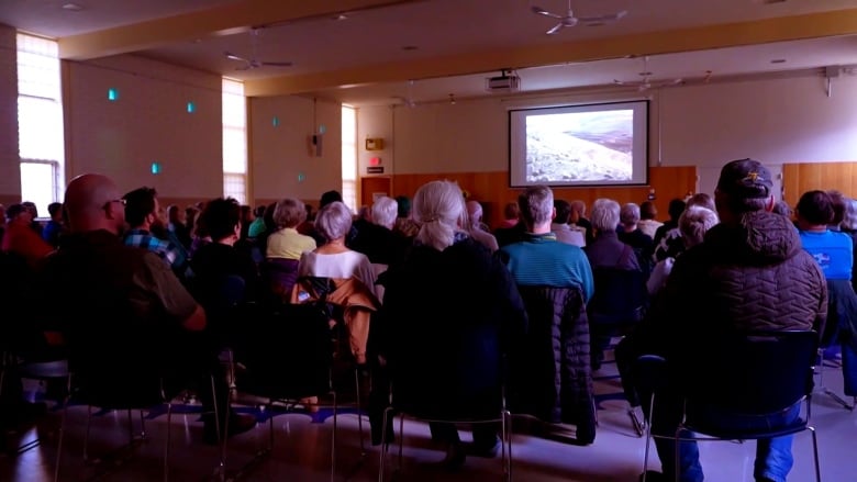 People gather in a room to watch a documentary.