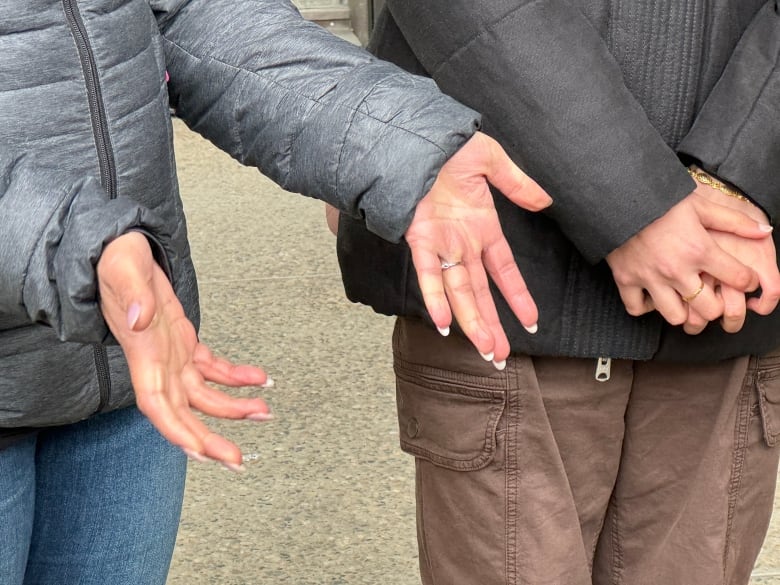 A view of two people standing, only visible from the chest down, and their hands clasped together.