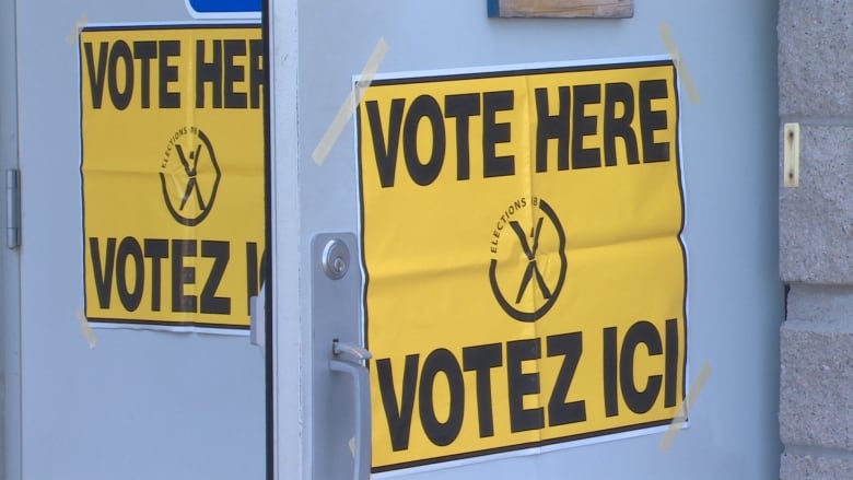 Two yellow signs that say "Vote Here"