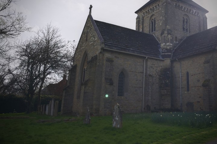 A photo of an orb floating over a gravestone in a churchyard.