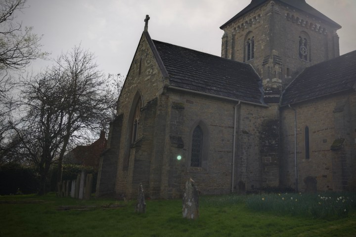 A photo of an orb floating over a gravestone in a churchyard.