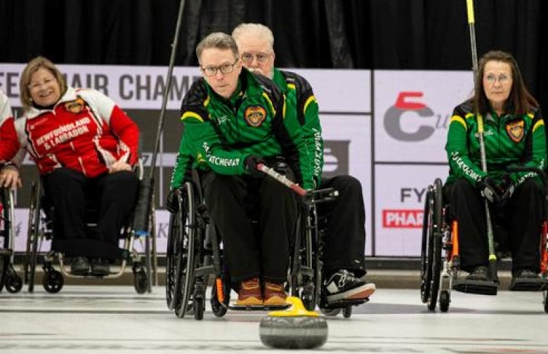 A photo of Gil Dash in his wheelchair and green jersey at the wheelchair curling championship finals. 