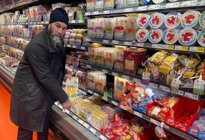 A man  points to a pack of cheese in a grocery store