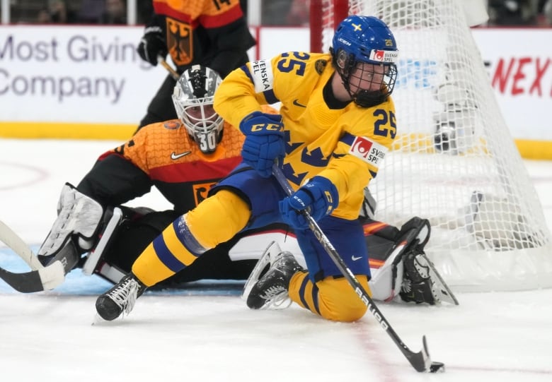 A hockey player in a Sweden jersey carries the puck in front of a German goaltender.