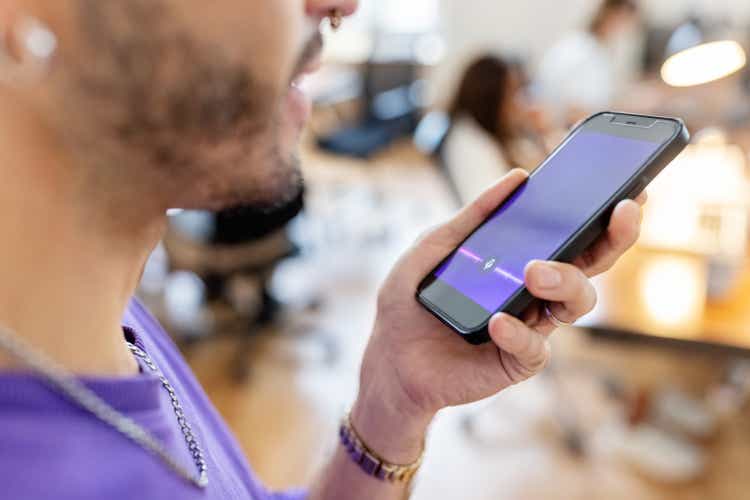 Close-up of man recording voice message on cellphone at office