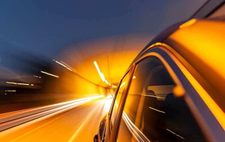 Hybrid car drives out of tunnel while night.