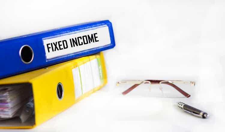 FIXED INCOME text on blue folder with pen, glasses on white background