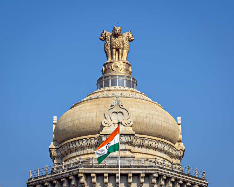 Close up image of dome of largest legislative building in India - Vidhan Soudha , Bangalore with nice blue sky background. Translation of text mentioned is Government work is God