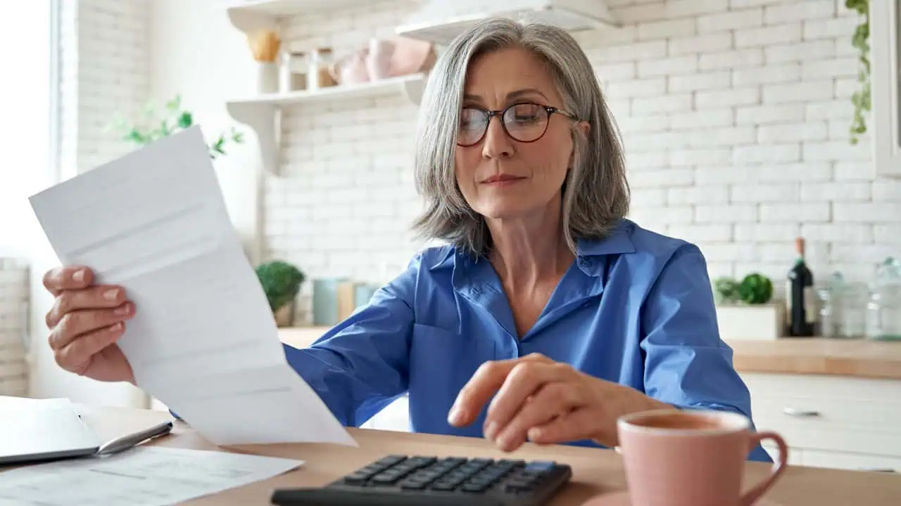 woman holding paper bill using calculator