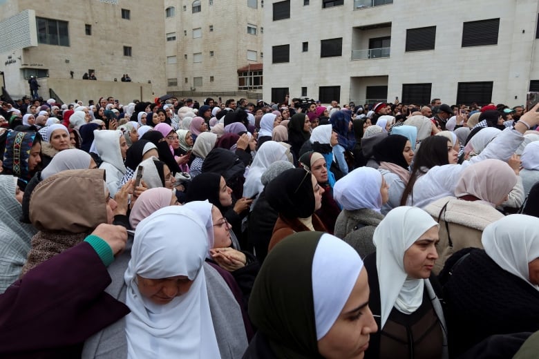 Dozens of women in headscarves are shown at a public gathering outdoors.