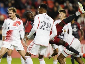 Toronto FC's Prince Osei Owusu (99) tumbles as he scores as New England Revolution's Mark-Anthony Kaye (28) looks on during second half MLS soccer action in Toronto on Saturday, April 20, 2024.