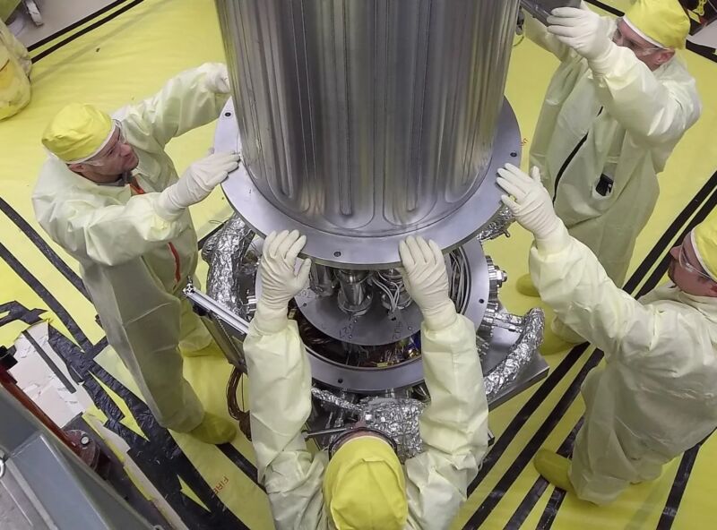 Engineers from NASA and the National Nuclear Safety Administration lower the wall of a vacuum chamber around the KRUSTY experiment, the Kilowatt Reactor Using Stirling Technology.