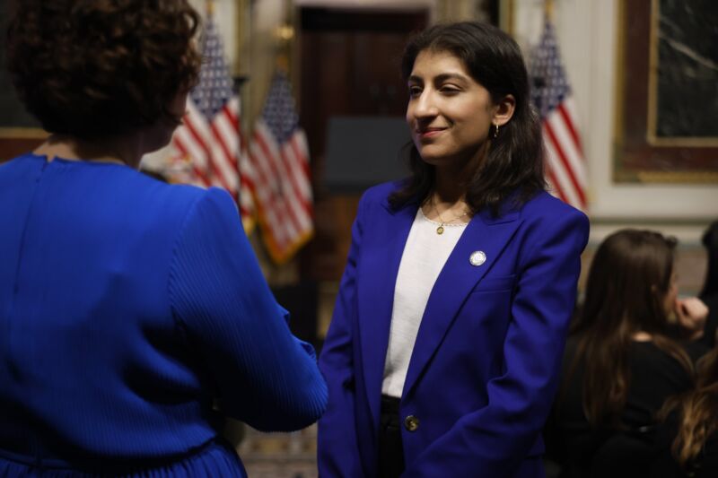 Federal Trade Commission Chair Lina Khan smiles while talking with people at an event.