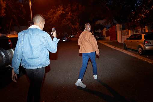 Man photographing friend on smart phone at street