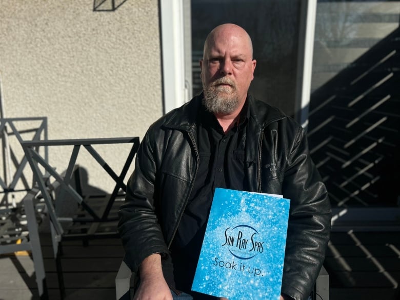 A man in black holds a blue file folder.